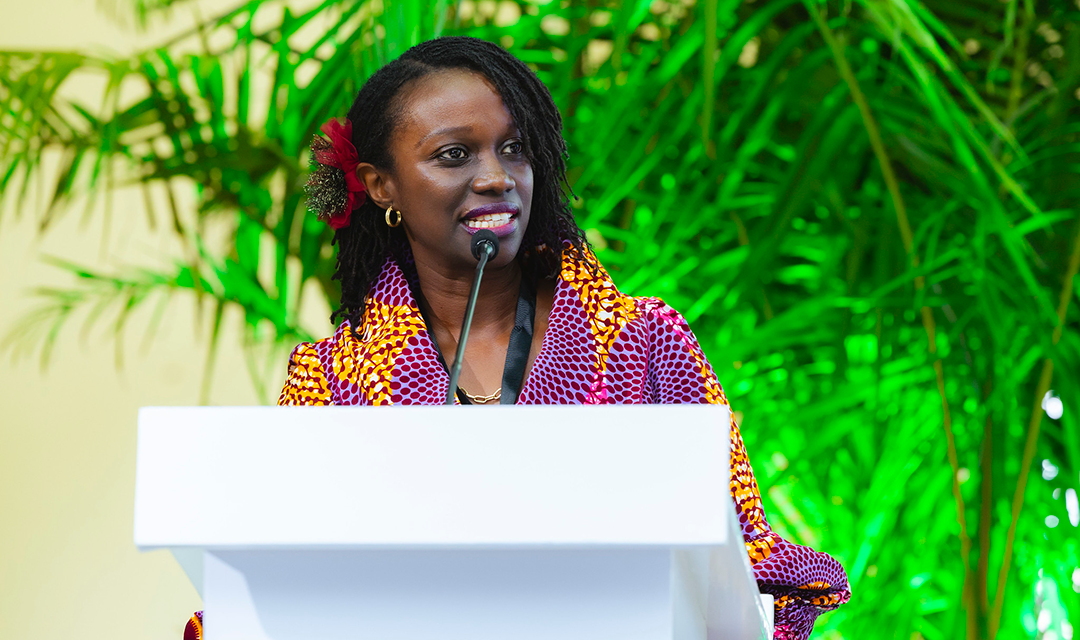 A woman in a colorful shirt at a podium speaking