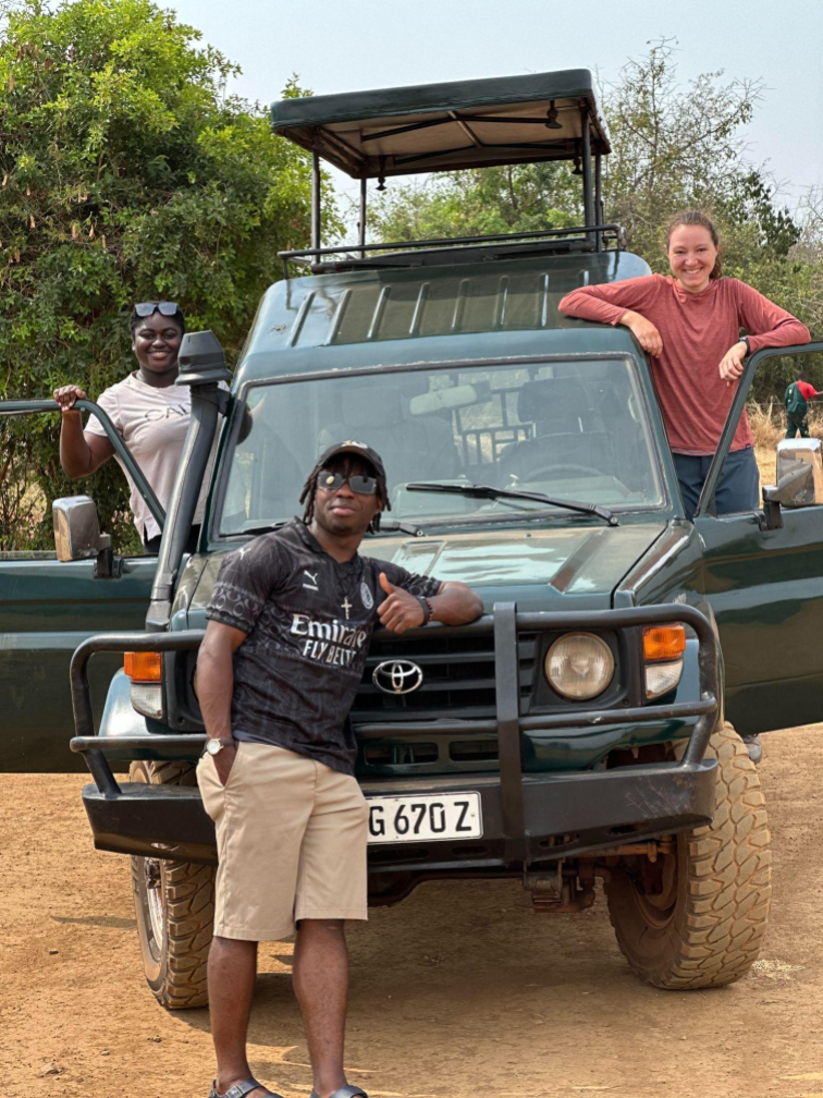 Three students by a car in Rwanda