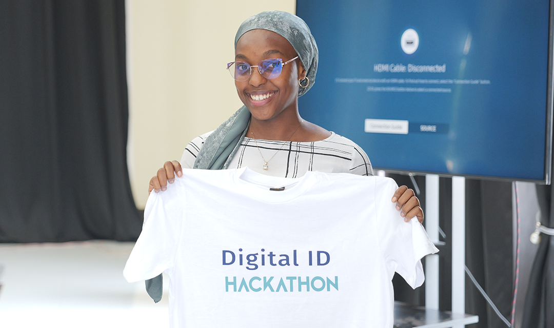 Woman holding up shirt with hackathon logo