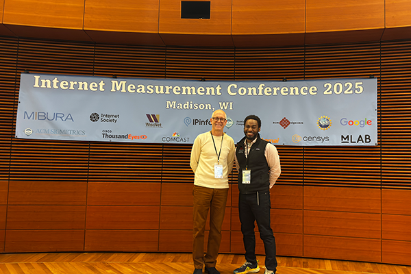 Two people standing by a banner