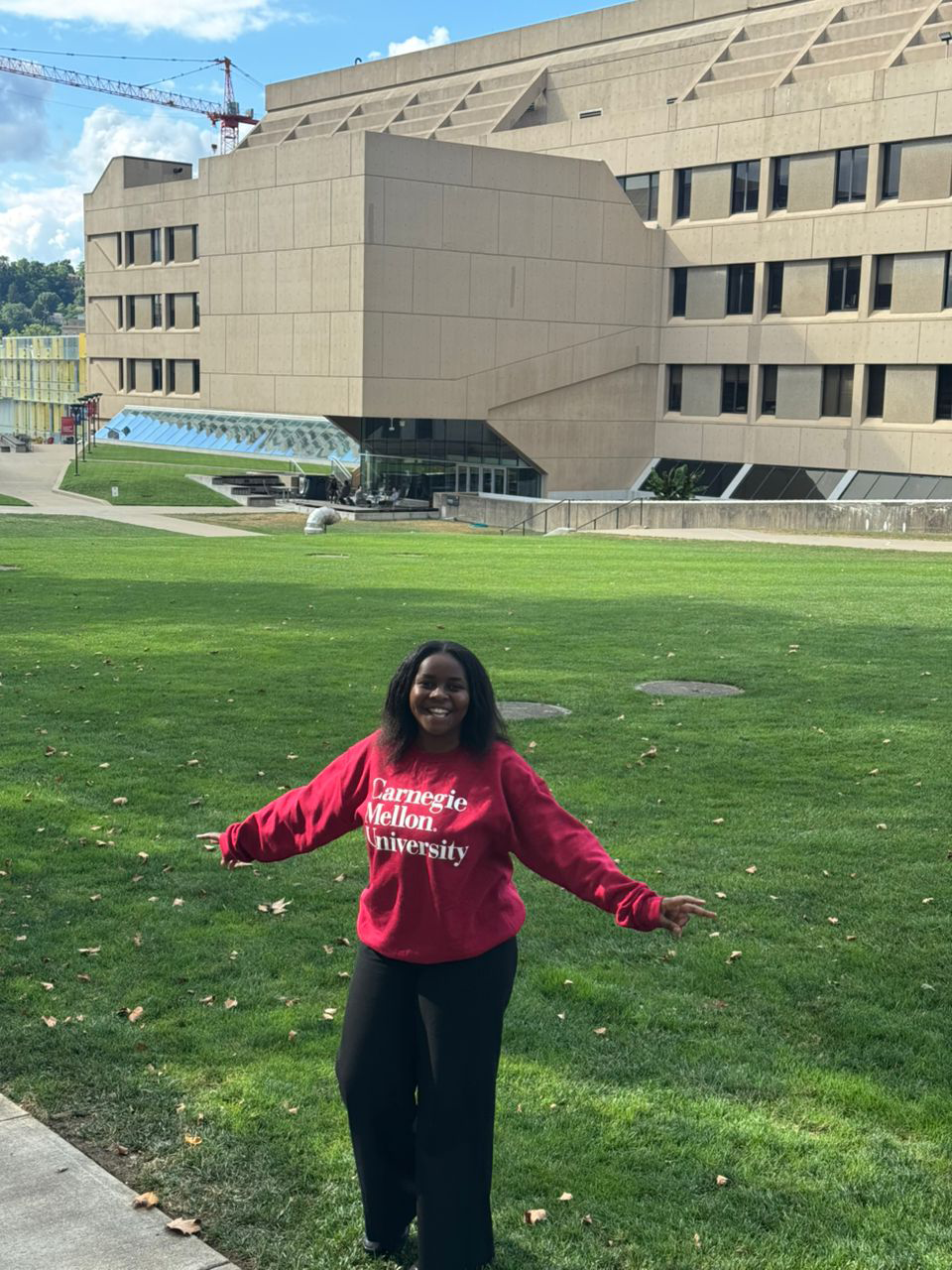 Student standing in front of Wean hall wearing a CMU sweatshirt