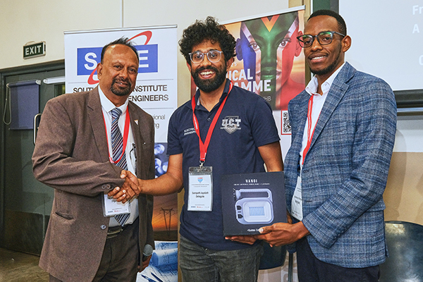 Aman holds a box that says Hanoi while two other men shake hands