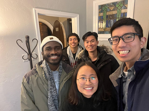 A group of students all smiling inside a private home