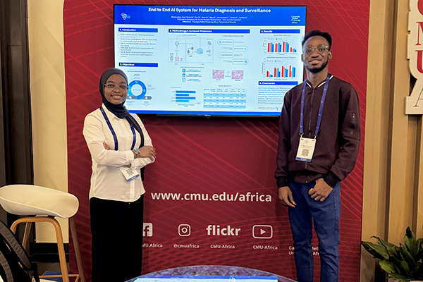 Two students in front of a powerpoint presentation