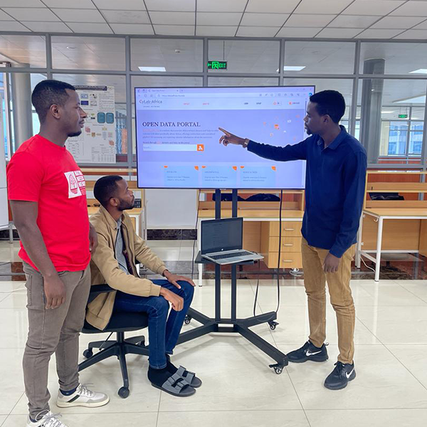 Three men standing by a tv monitor